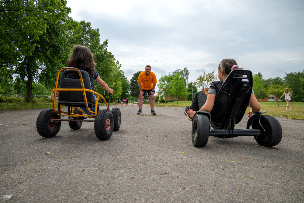 Två barn sitter i varsin fyrhjuling, bilden är tagen underifrån